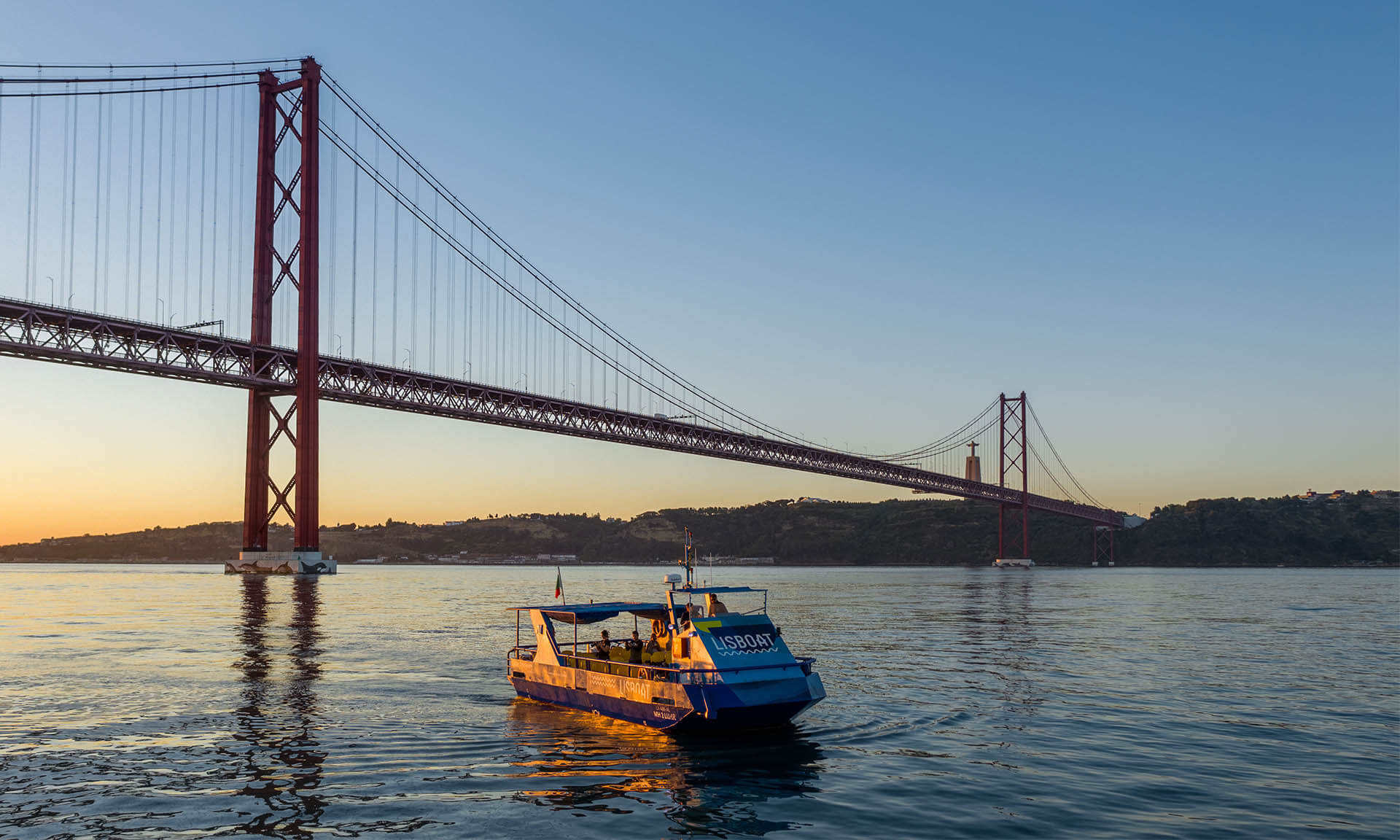 A tourist boat cruising in Lisbon at sunset.